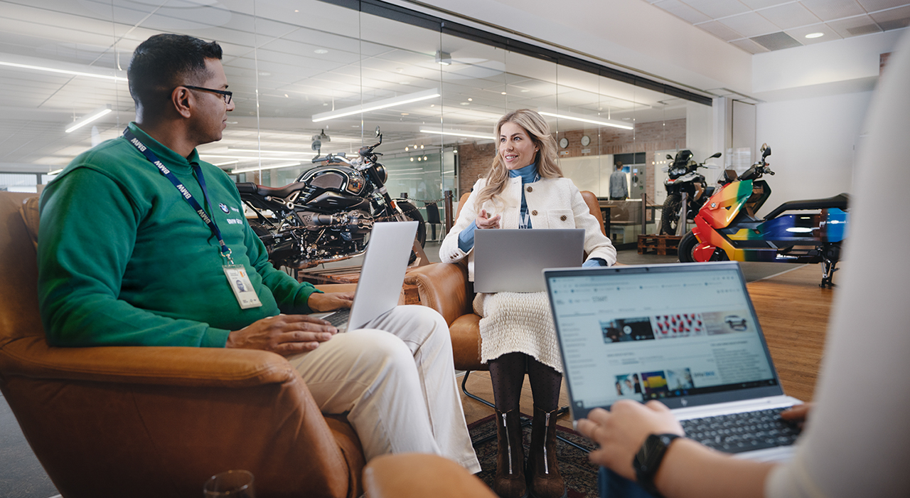 Two BMW employees are working together on a laptop and laughing.