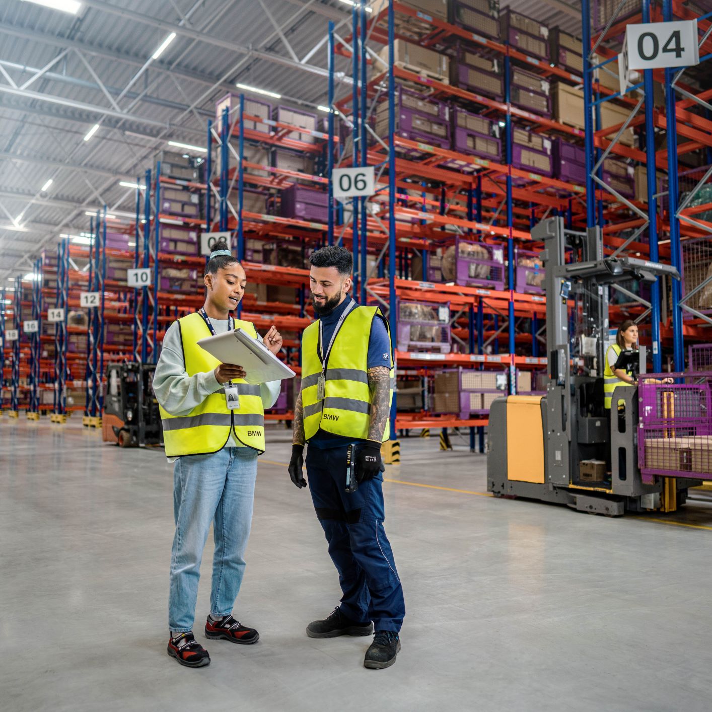 The picture shows two BMW logistics employees talking in a warehouse.