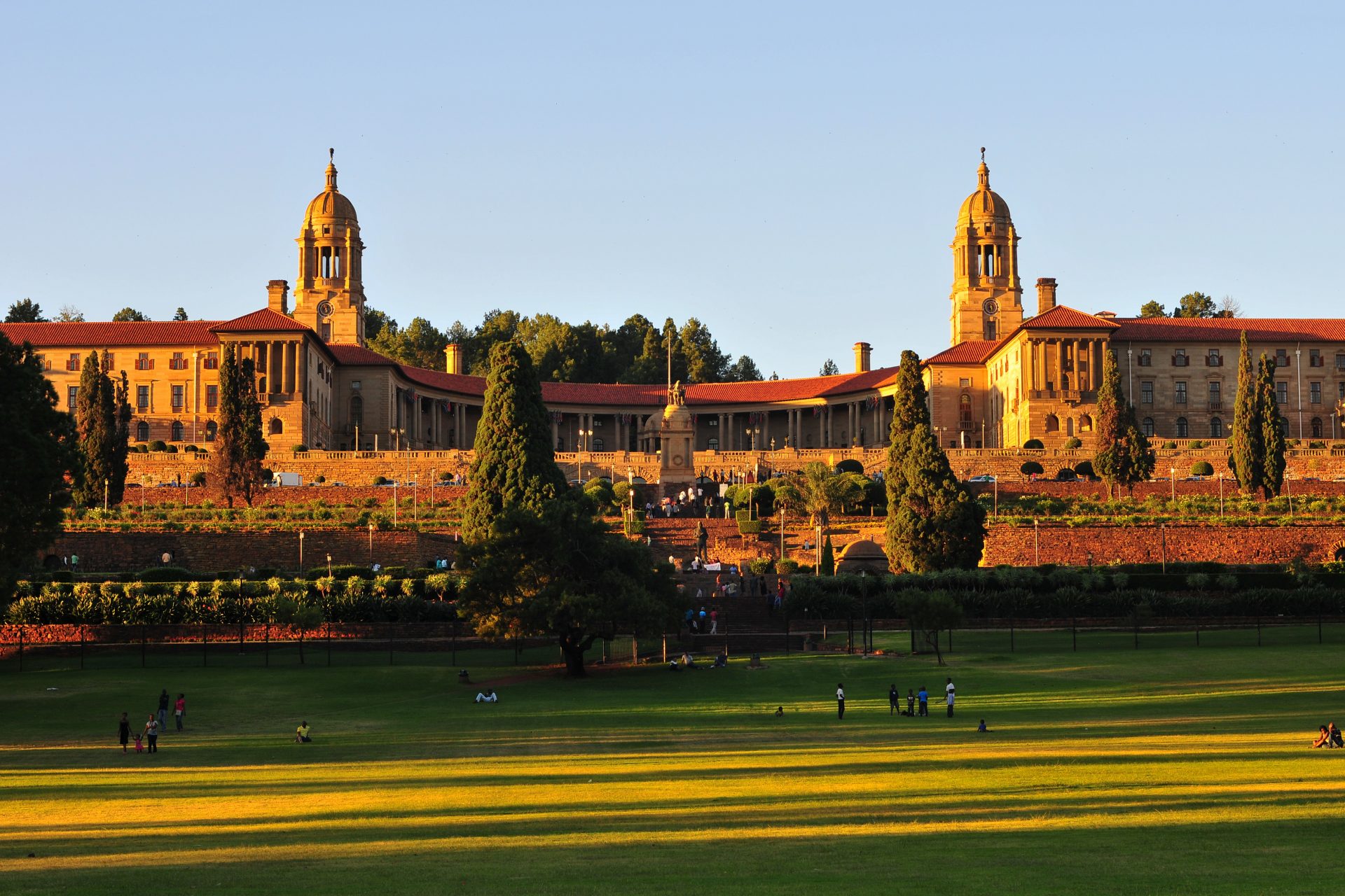 "South African Union Buildings seen here at sundown. The Union Buildings were built from light sandstone and designed by the Sir Herbert Baker in the English monumental style. The Buildings are over 275 m long and a semi-circular shape, with the two wings at the sides that represent the union of a formerly divided people. (English and Afrikaans). The Union Buildings are considered by many to be the architect's greatest achievement and a South African architectural masterpiece. The cornerstone was laid in November 1910. Requiring over 1,265 workers over 3 years to build, the structure was completed in 1913. Today, the official seat of the South African government and also the offices of the President of South Africa."