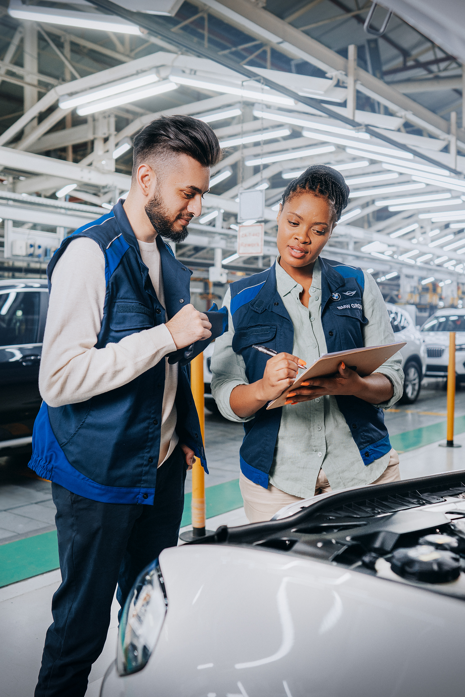 An intern and his supervisor working in the BMW production line.
