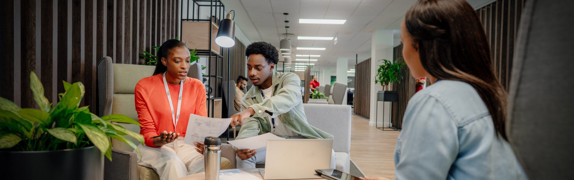 Three students having a conversation in a modern office environment.
